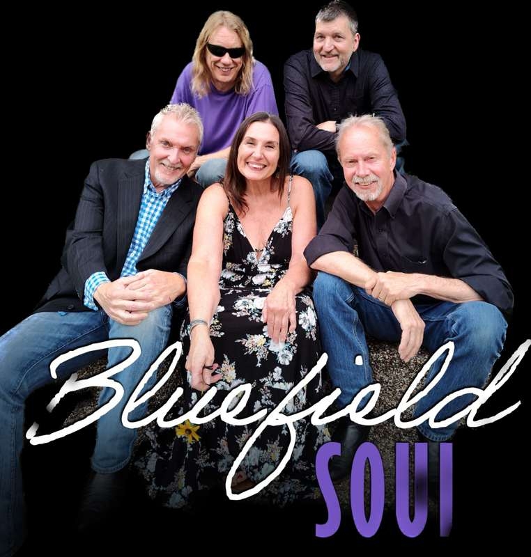 Five adults posing together for a group photo, the woman in a floral dress sits center with four men around her; bold white script text 'Bluefield' and purple 'SOUL' overlays on a black background.
